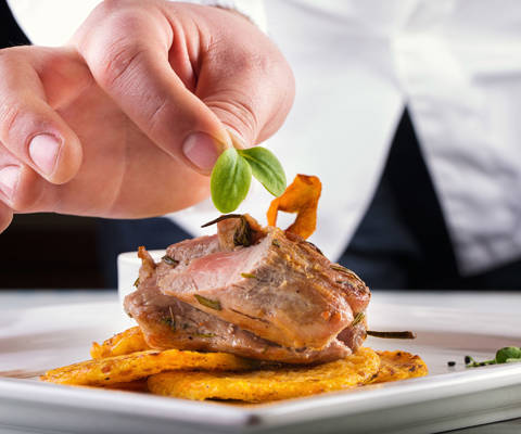 Chef garnishing a gourmet dish with fresh herbs