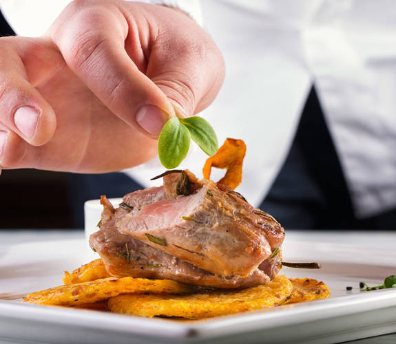 Chef garnishing a gourmet dish with fresh herbs