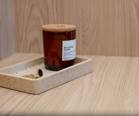 Wooden shelf with small ceramic plate holding jewelry and a relaxing room fragrance.