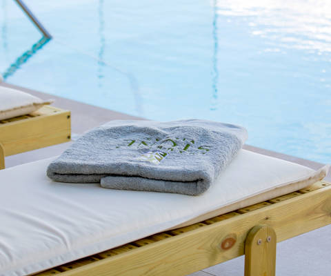 Poolside sunbed with folded towel overlooking the swimming pool