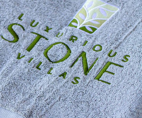 Close-up of a towel with Luxurious Stone Villas embroidered logo.