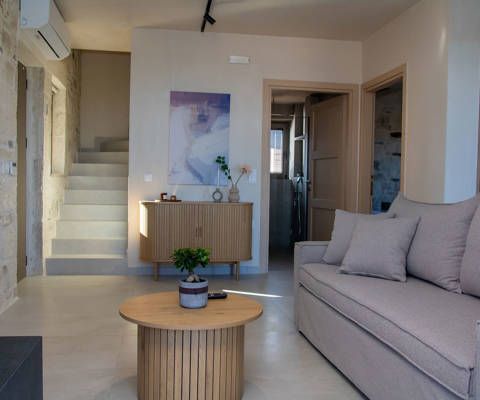 Comfortable Living room with air conditioning, sideboard with modern painting above it, staircase leading upstairs and doors to other rooms