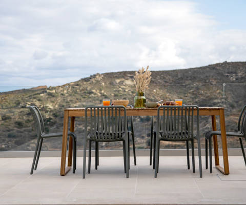 Outdoor dining table with view of the hill and open sky.