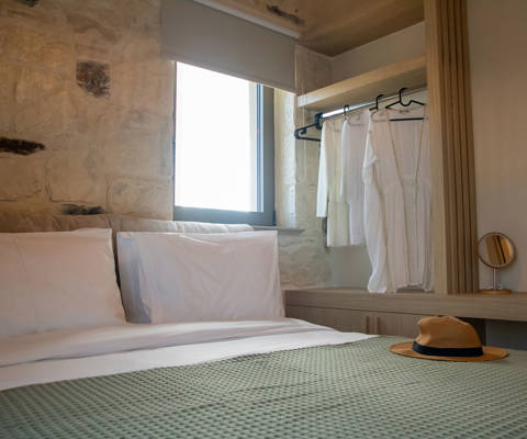 Bedroom interior with double bed under a window and stand with hangers, close-up shot