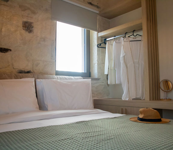 Bedroom interior with double bed under a window and stand with hangers, close-up shot