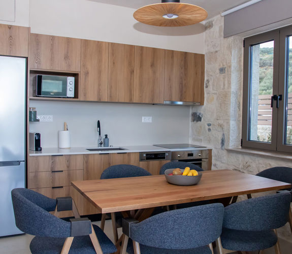 Modern kitchen with wooden cabinets, dining table, large window, and stainless steel appliances