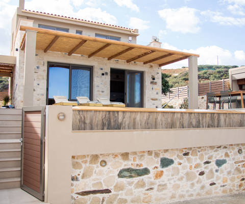 Front view of the beautiful stone villa with a gated staircase leading to a large veranda and pool area