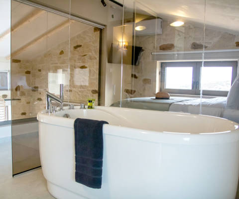 Elegant bathroom in loft area with freestanding bathtub and glass walls