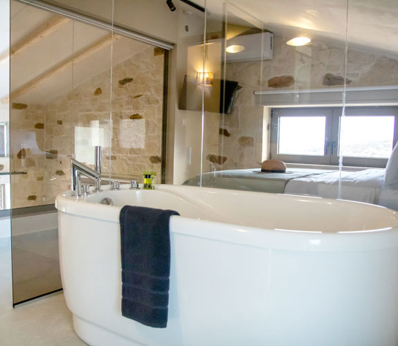Elegant bathroom in loft area with freestanding bathtub and glass walls